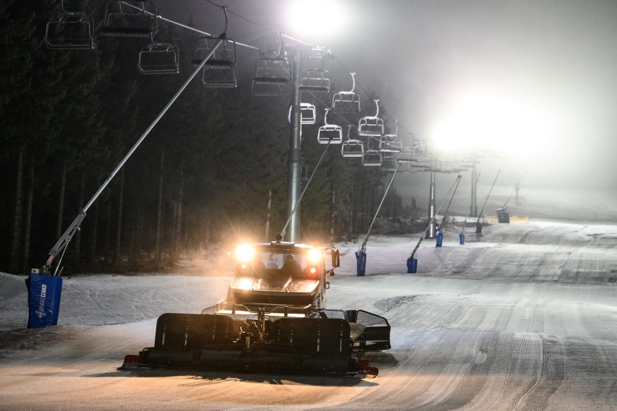 Eine Pistenraupe schiebt Schnee auf der Skipiste neben dem Hexenritt-Sessellift auf dem Wurmberg im Harz.