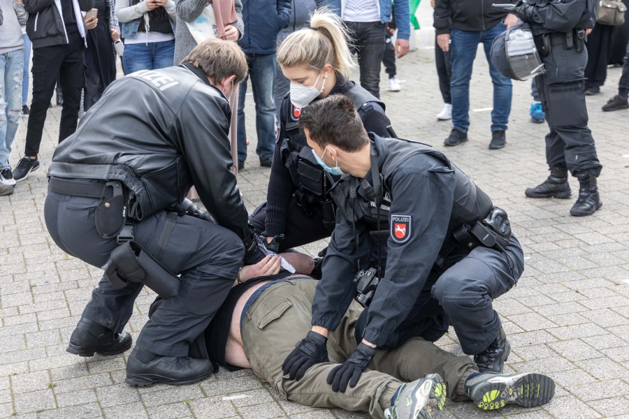 Polizisten nehmen einen Demonstranten fest.