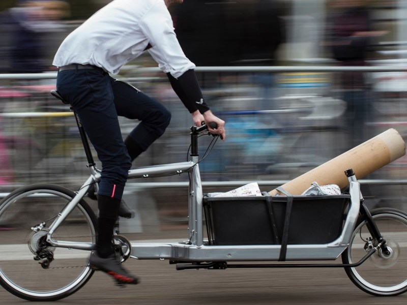 Mann fährt auf einem Lastenfahrrad