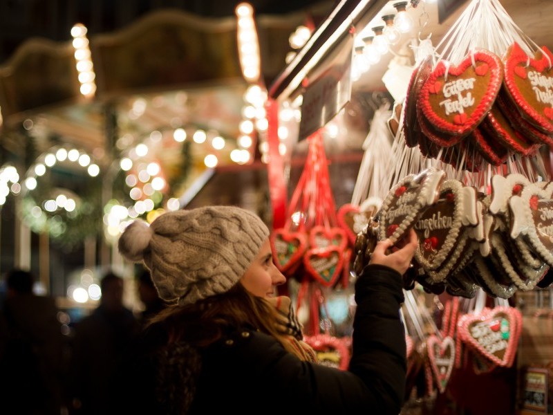Frau schaut sich auf dem Weihnachtsmarkt Lebkuchenherzen an