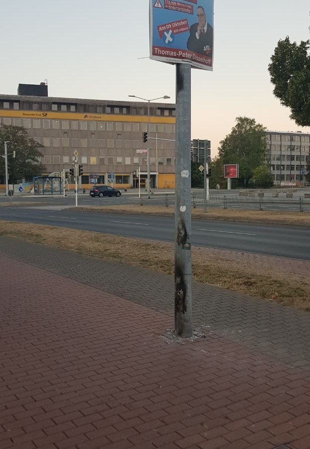 Abgebranntes Parteiplakat steht gegenüber vorm Rathaus