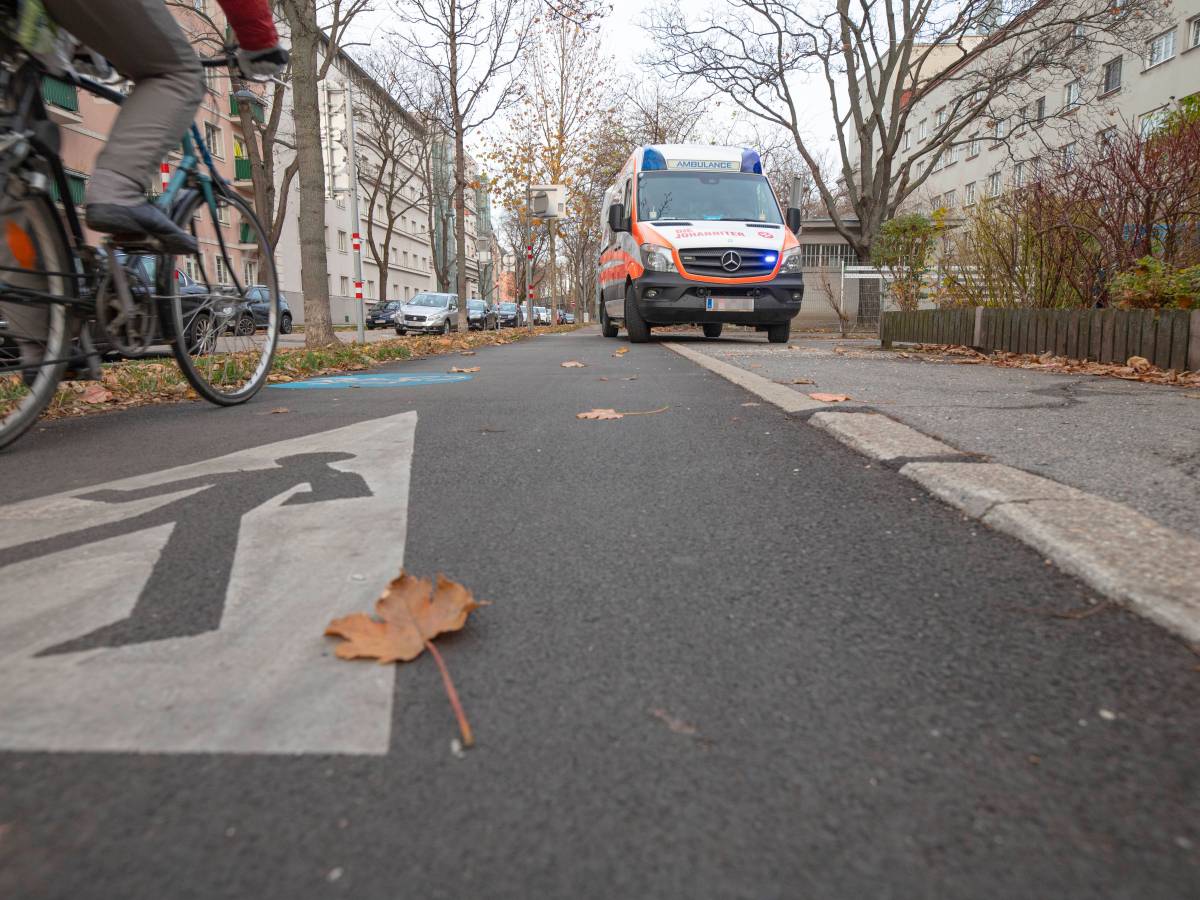 Fahrrad fährt auf Radweg, Rettungswagen steht dort