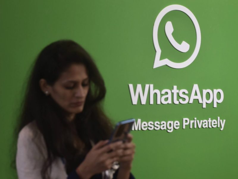 Whatsapp Logo, Frau schaut auf ihr Handy