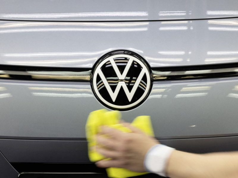 Person wischt mit einem Tuch über VW Logo am ID.3
