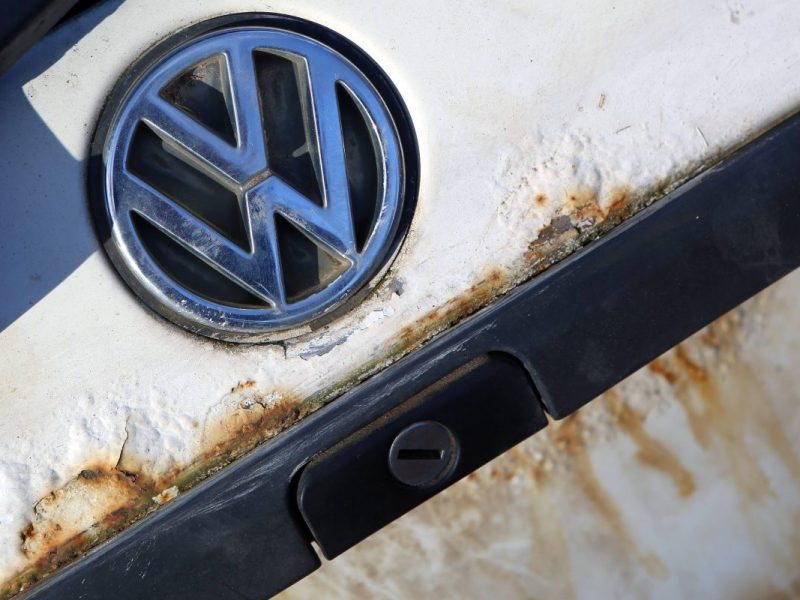 Ein Volkswagen Logo auf dem verrosteten Heck eines alten Golf.