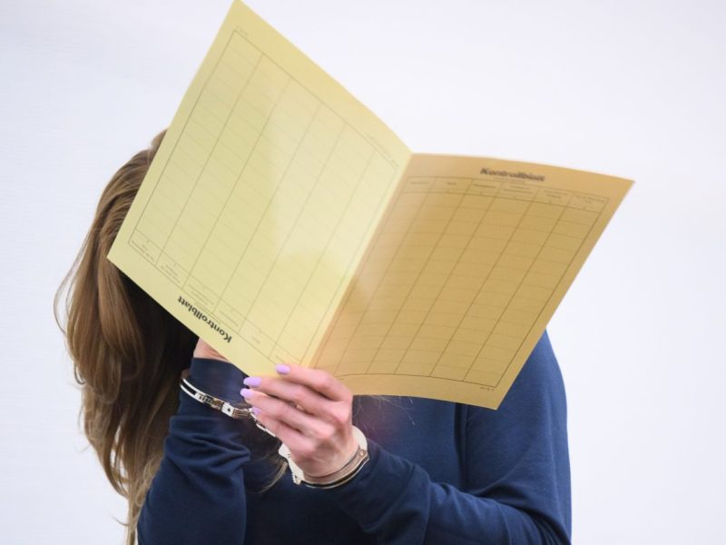 Die Angeklagte kommt mit verdecktem Gesicht in den Gerichtssaal im Landgericht. Eine Frau und ein Mann sind wegen Mordes angeklagt, weil sie den Unfalltod von zwei kleinen Jungen verursacht haben sollen. Beiden wird vorgeworfen, sich auf einer Landstraße bei Barsinghausen ein verbotenes Autorennen geliefert zu haben.