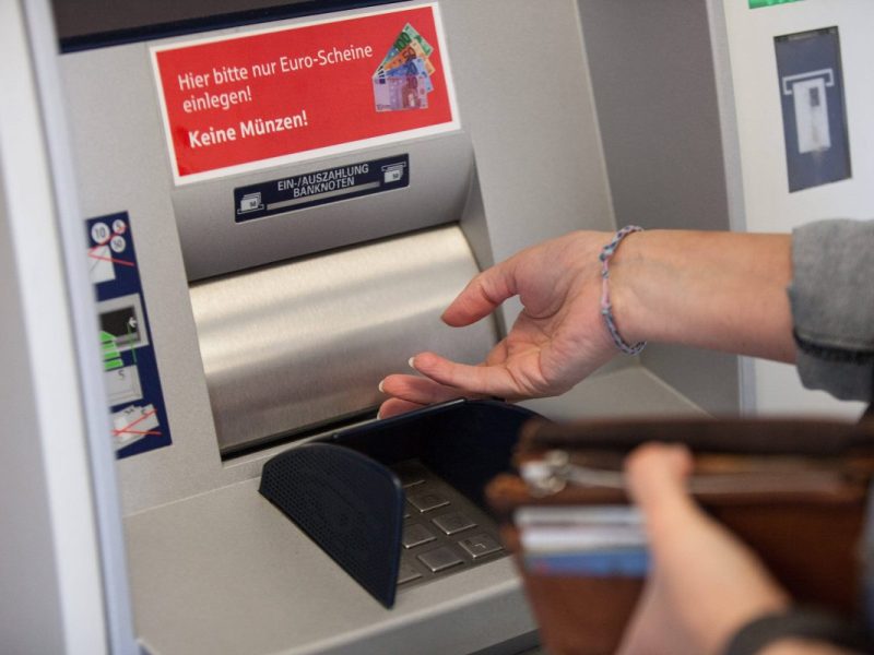 Frau hebt Geld am Geldautomaten ab