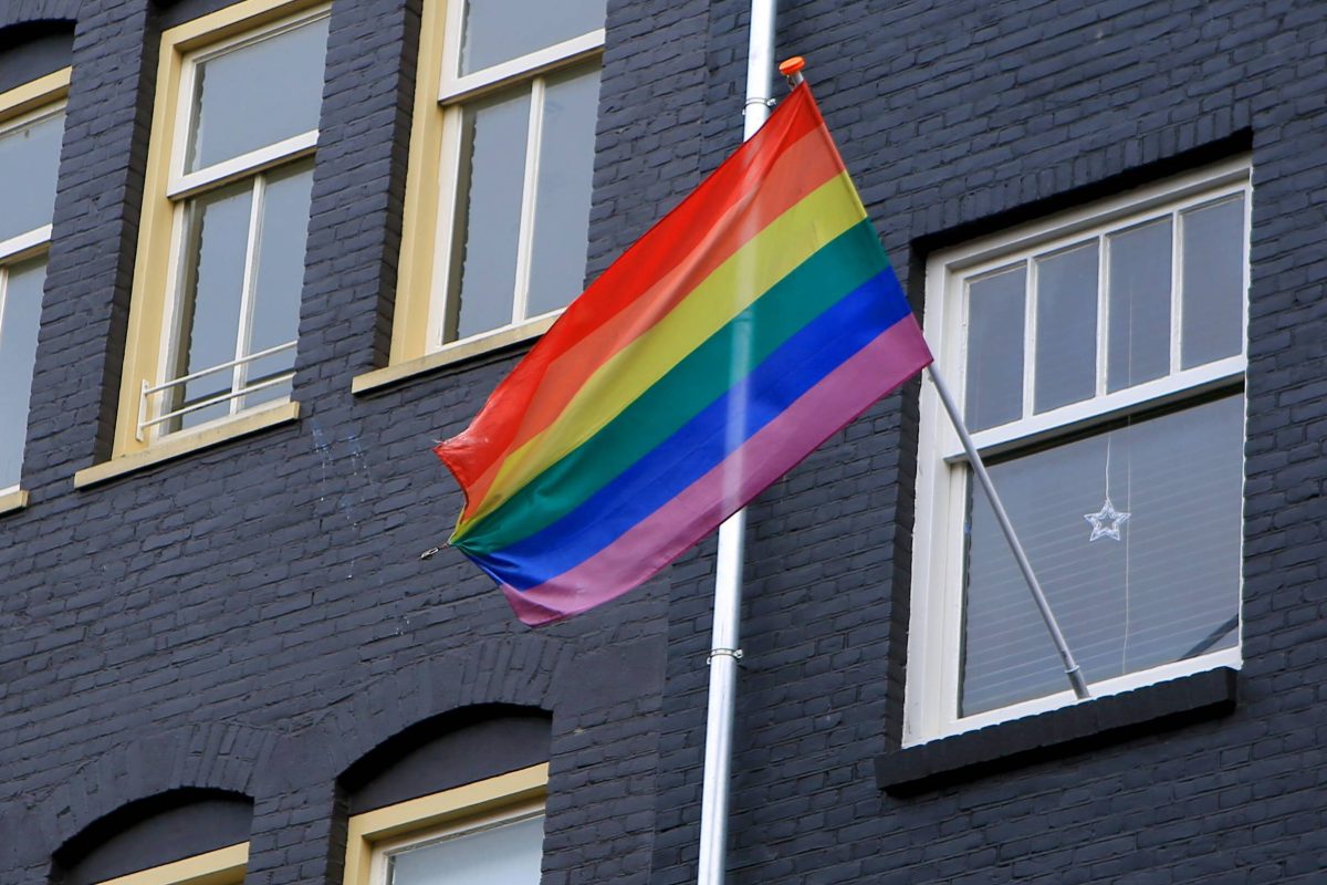 Eine Regenbogenfahne weht an einem haus.