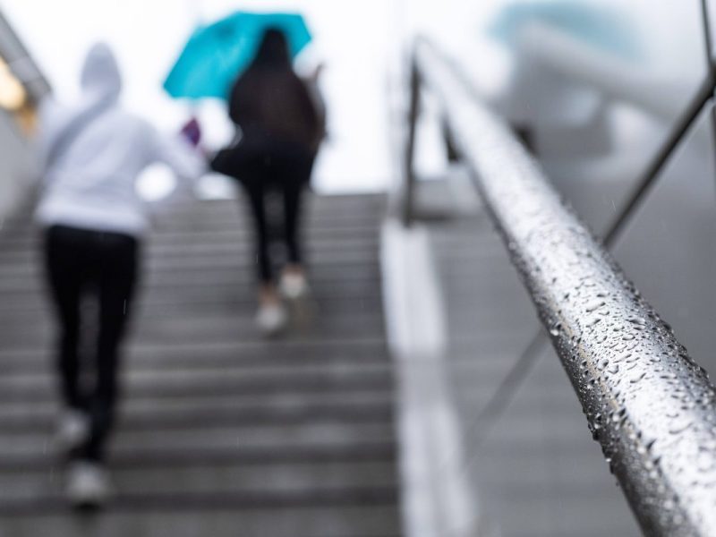 Personen gehen im Regen die Treppe hoch
