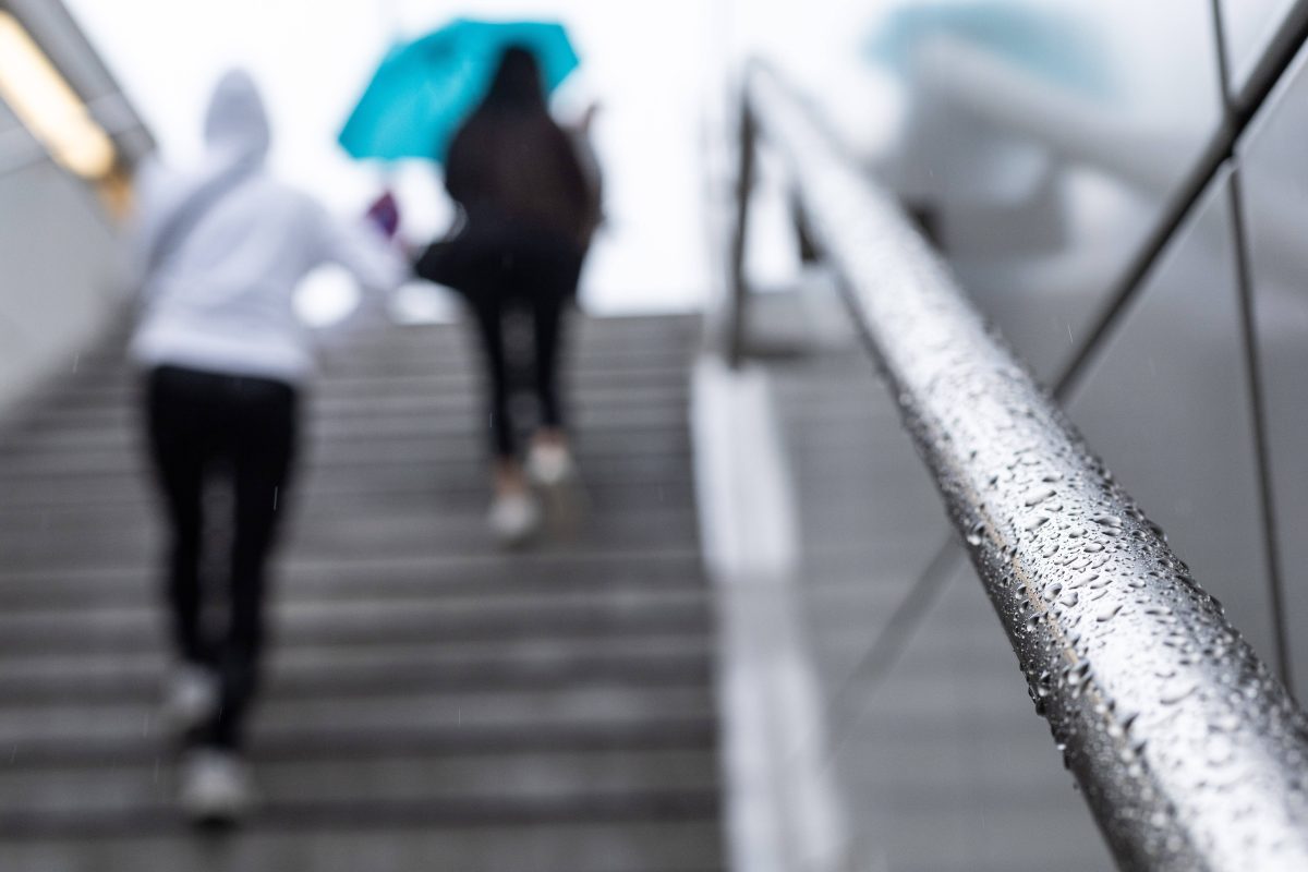 Personen gehen im Regen die Treppe hoch