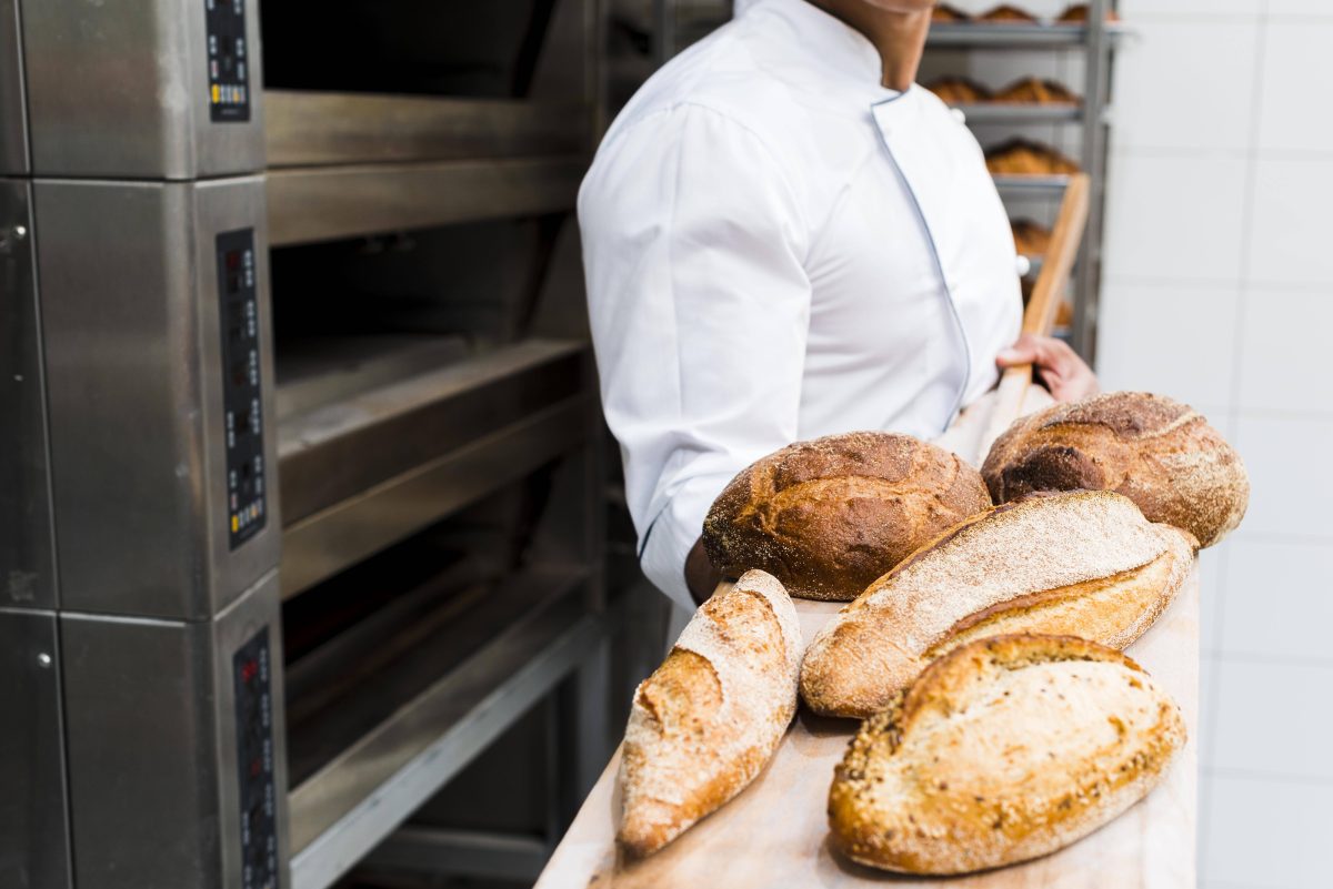 Bäcker hält frisches Brot auf einer Schaufel in die Kamera