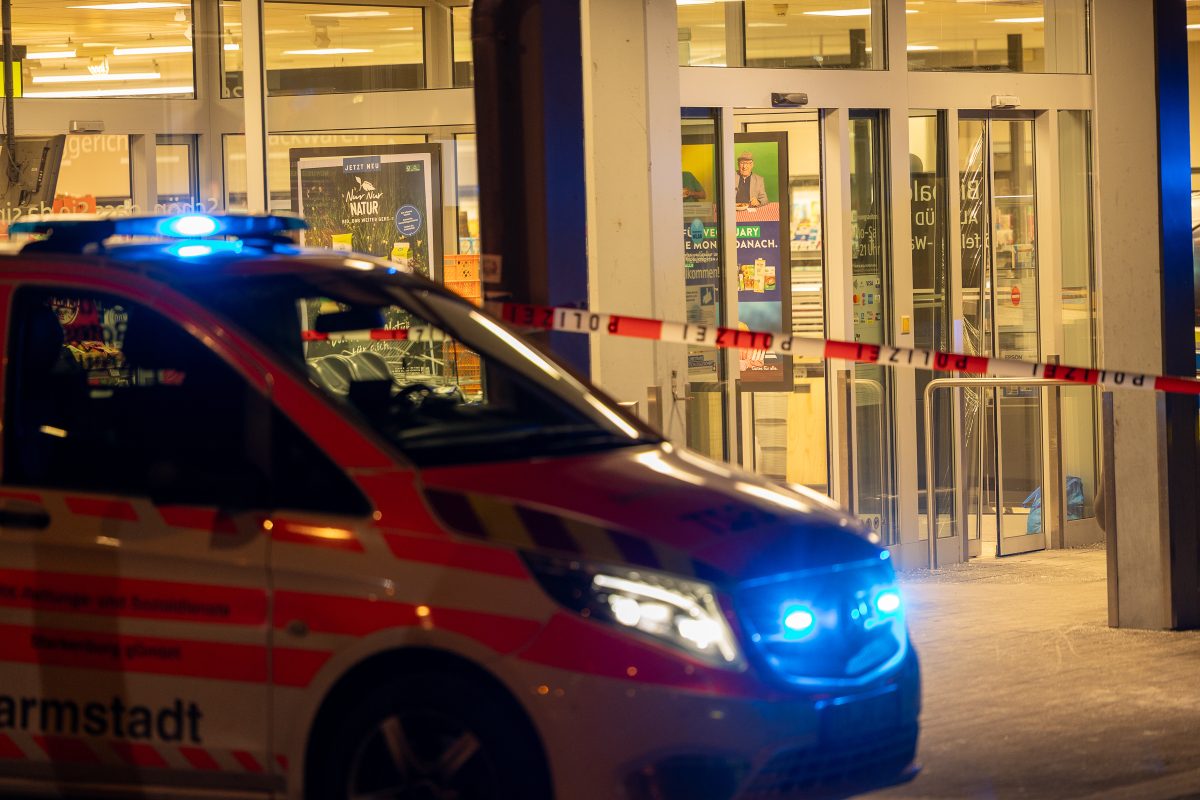 Ein Einsatzfahrzeug steht vor einem Supermarkt mit Blaulicht. Eine Frau wurde in dem Supermarkt erschossen. Der mutmaßliche Täter brachte sich danach selbst um.