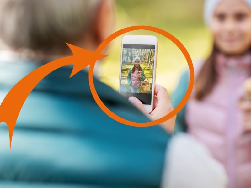 Ein Mädchen lässt sich mit einem Smartphone aufnehmen wie es in Niedersachen im Wald Pilze sammelt.