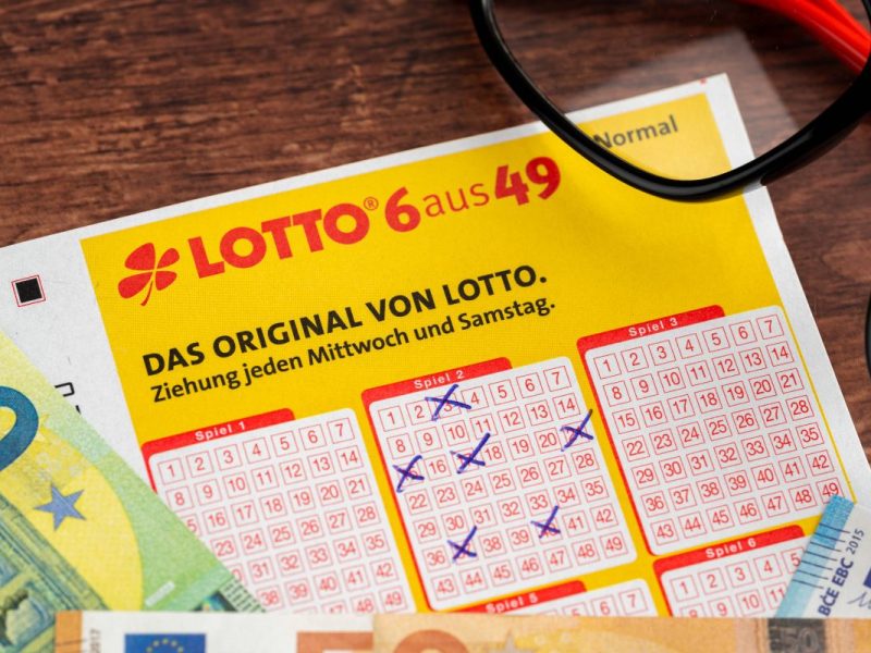 Lottoschein von Lotto 6 aus 49 mit ausgefüllten Tippfeldern und Euro Geldscheinen