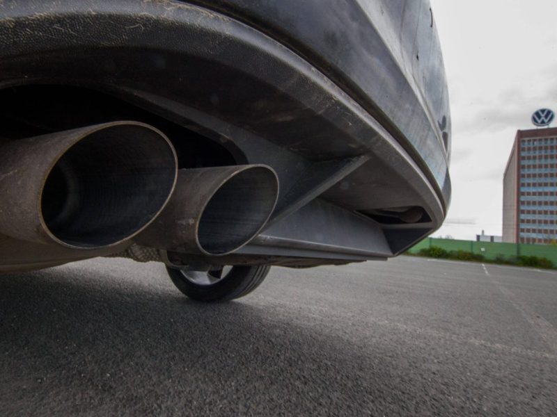 Auspuff eines Autos vor dem Hintergrund des VW-Markenhochhauses in Wolfsburg