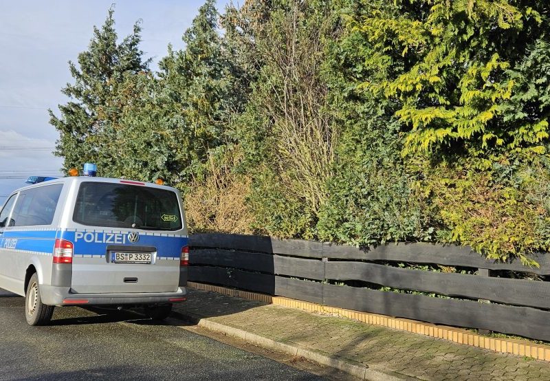 Ein Polizeibus steht am Rande von Wendeburg im Landkreis Peine in der Straße, in der eine 62-jährige Frau in einem Haus tot aufgefunden wurde.