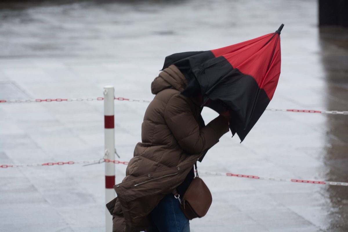 Eine Frau hat aufgrund starker WindbÃ¶en Probleme ihren Regenschirm festzuhalten. (Symbolbild) fÃ¼r das Wetter in Niedersachsen.