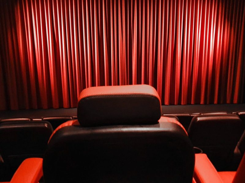 Ein leerer Kinosaal mit roten Sitzen und geschlossenen Vorhängen auf der Bühne im Kino (Symbolbild für das Astor Braunschweig)