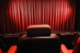 Ein leerer Kinosaal mit roten Sitzen und geschlossenen Vorhängen auf der Bühne im Kino. Symbolbild für Kinobesuche in Braunschweig