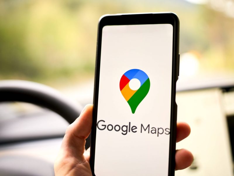 Google Maps Navigation Logo auf einem Smartphone in einem Auto vor einem Navi bzw. Navigationsgerät (Symbolbild für die Umbenennung einer Straße in Braunschweig)