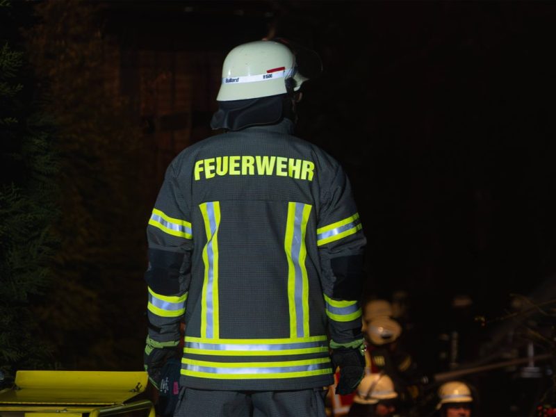 Ein Feuerwehrmann steht in Feuerwehruniformen bei einem Feuer, Brand. Niedersachsen (Symbolbild)