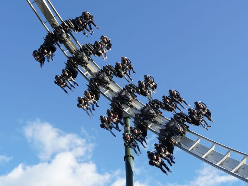 Mehrere Menschen haben Spaß auf einem Fahrgeschäft im Heide Park bei blauem Himmel (Symbolbild)